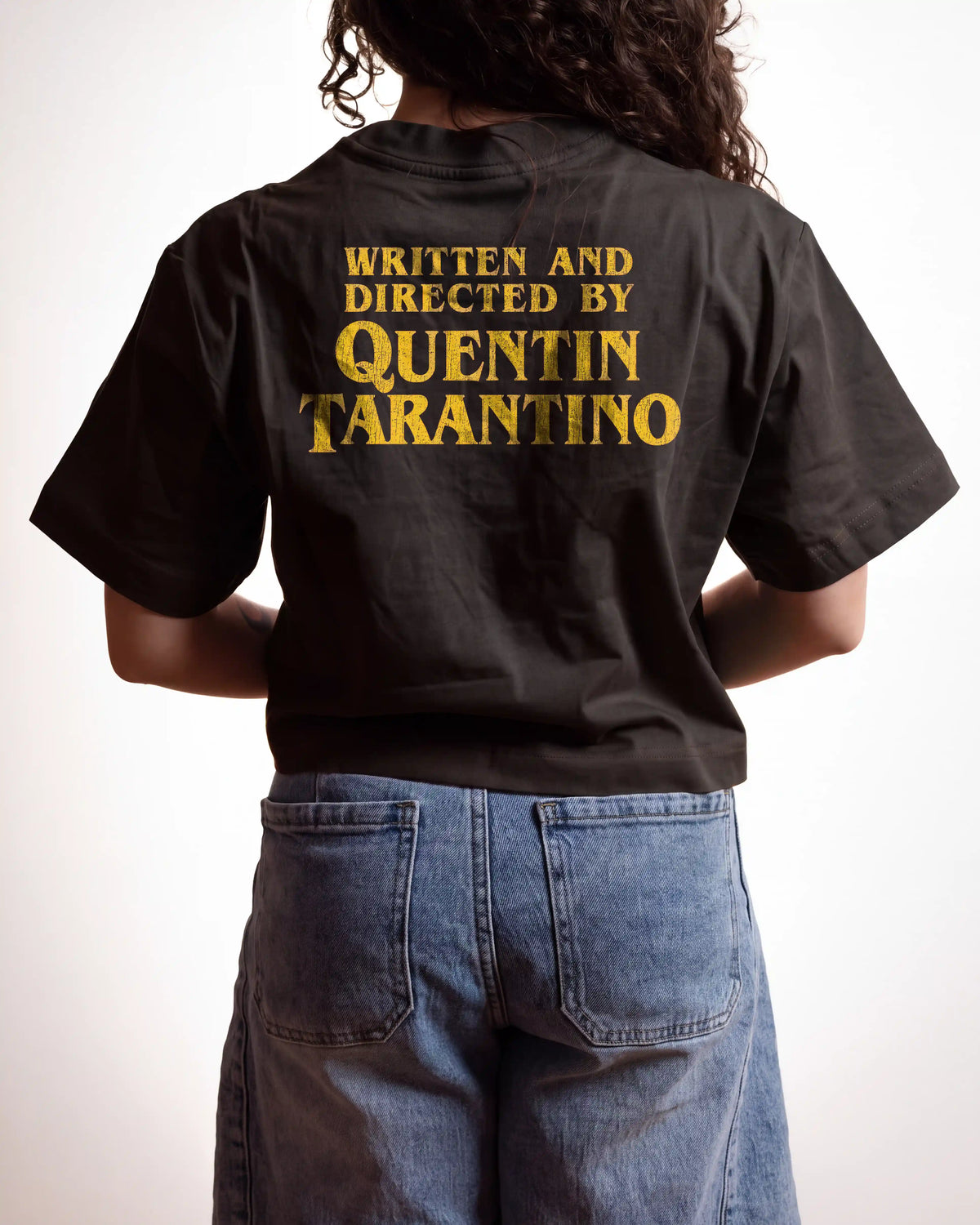 a woman wearing an off black crop top with a "written and directed by Quentin Taratino" text on it