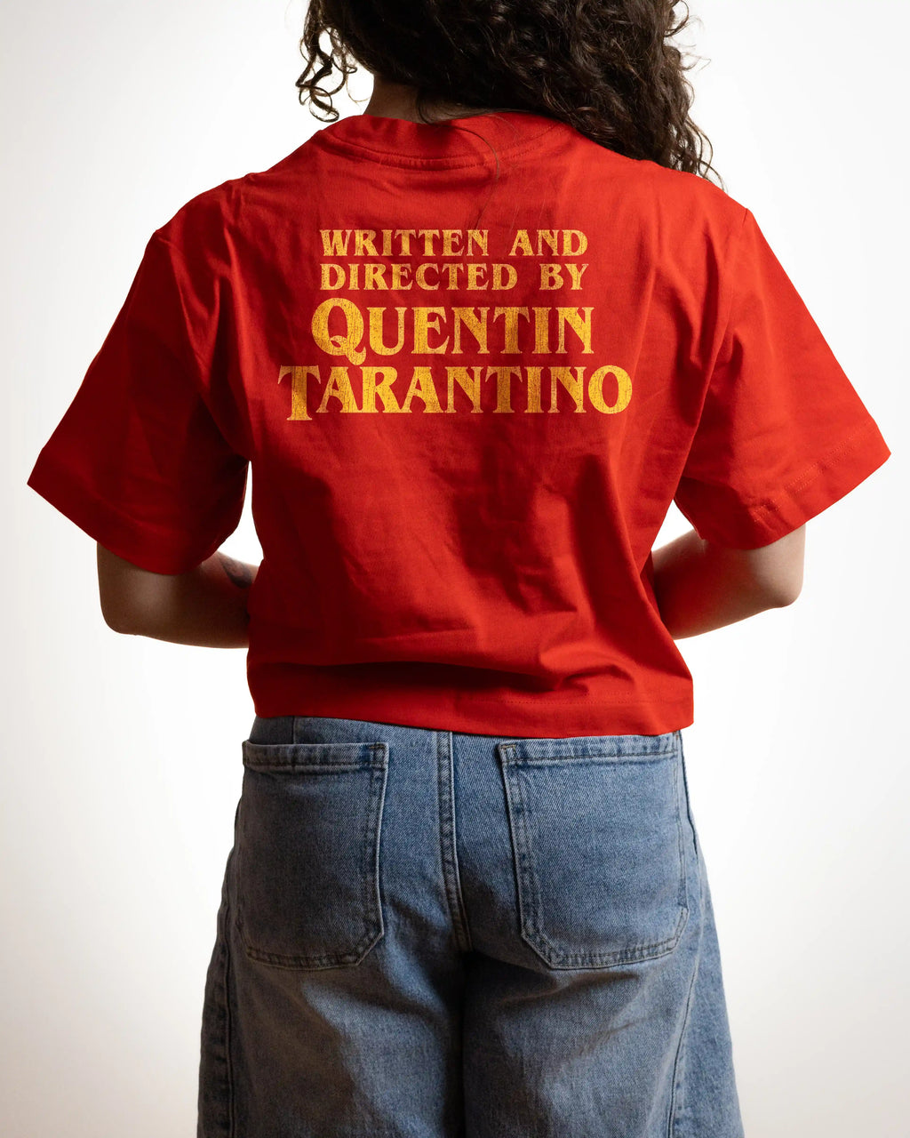 a woman wearing a red crop top with a "written and directed by Quentin Taratino" text on it