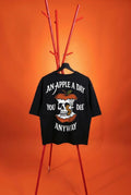 Black t-shirt with graphic design and text on a stand against an orange background