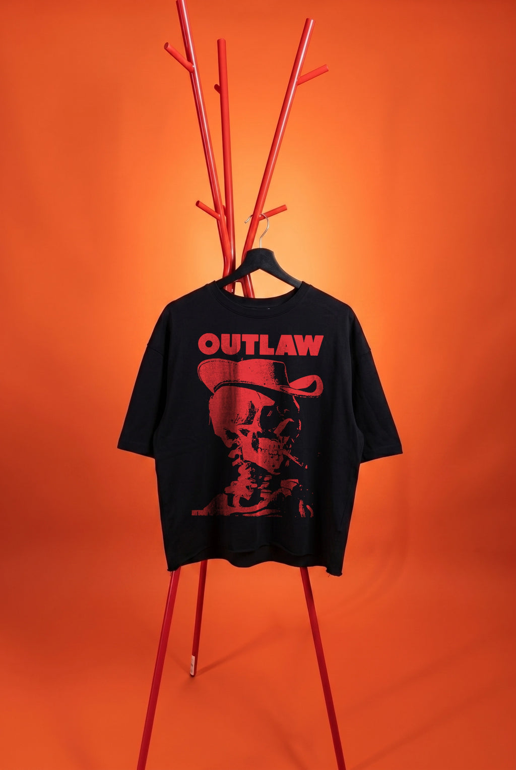 Black t-shirt with 'Outlaw' graphic on a red stand against an orange background