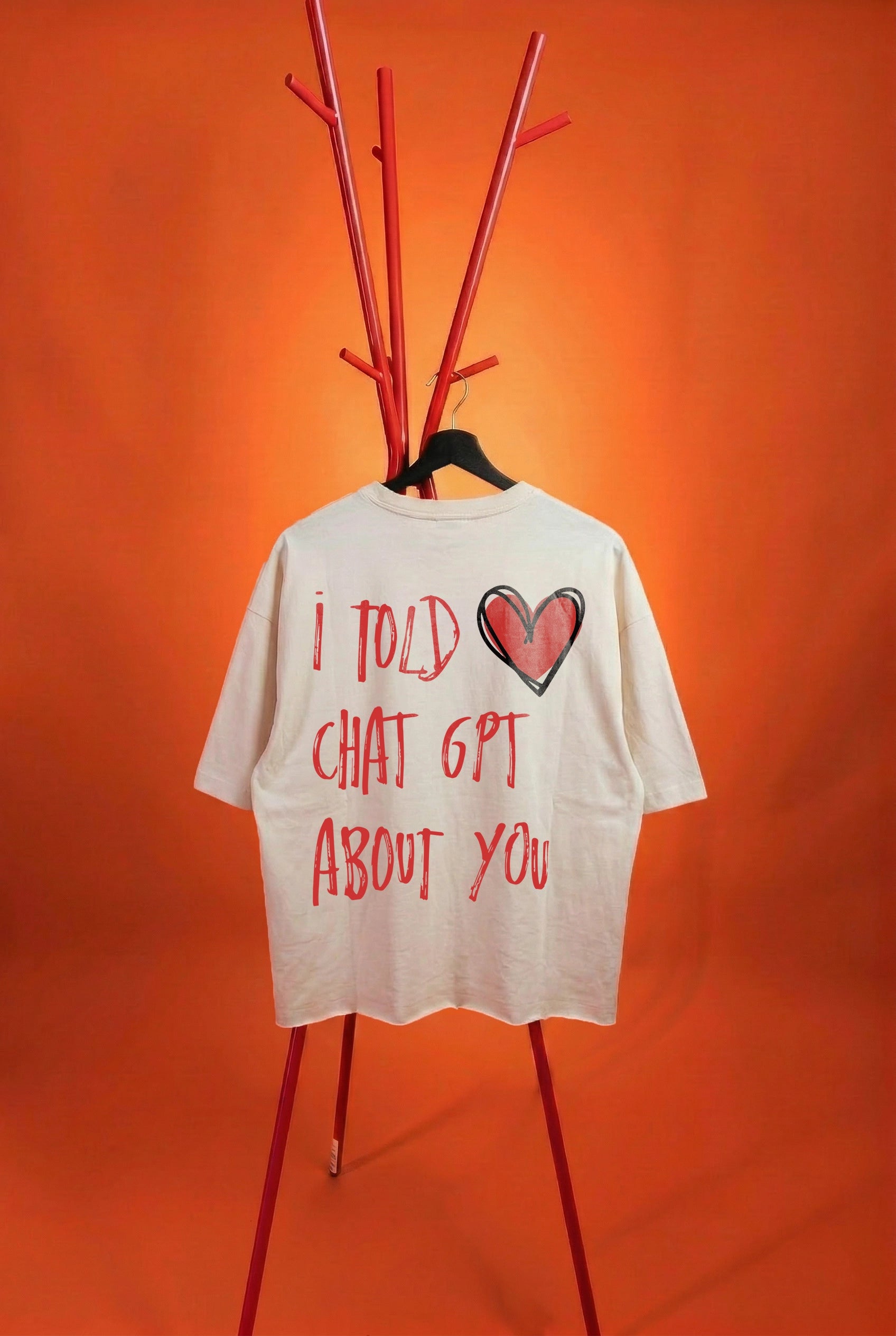 White t-shirt with red text and heart graphic on a stand against an orange background