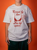 A person wearing an oversized white graphic T-shirt with red text reading 'Curved by Fate Not by option' and a red line-art illustration, posed against a solid orange background.