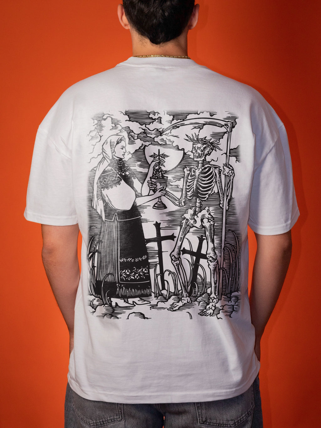A person viewed from the back wearing a white oversized T-shirt with a large black illustrated graphic on the back, standing against a solid orange background.