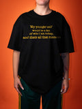 A person wearing an oversized black graphic T-shirt with yellow text that reads, 'My younger self would be a fan of who I am today, and thats all that matters,' posed against a solid orange background.