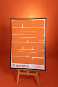 Poster with text 'IS BORING.' on an easel against an orange background