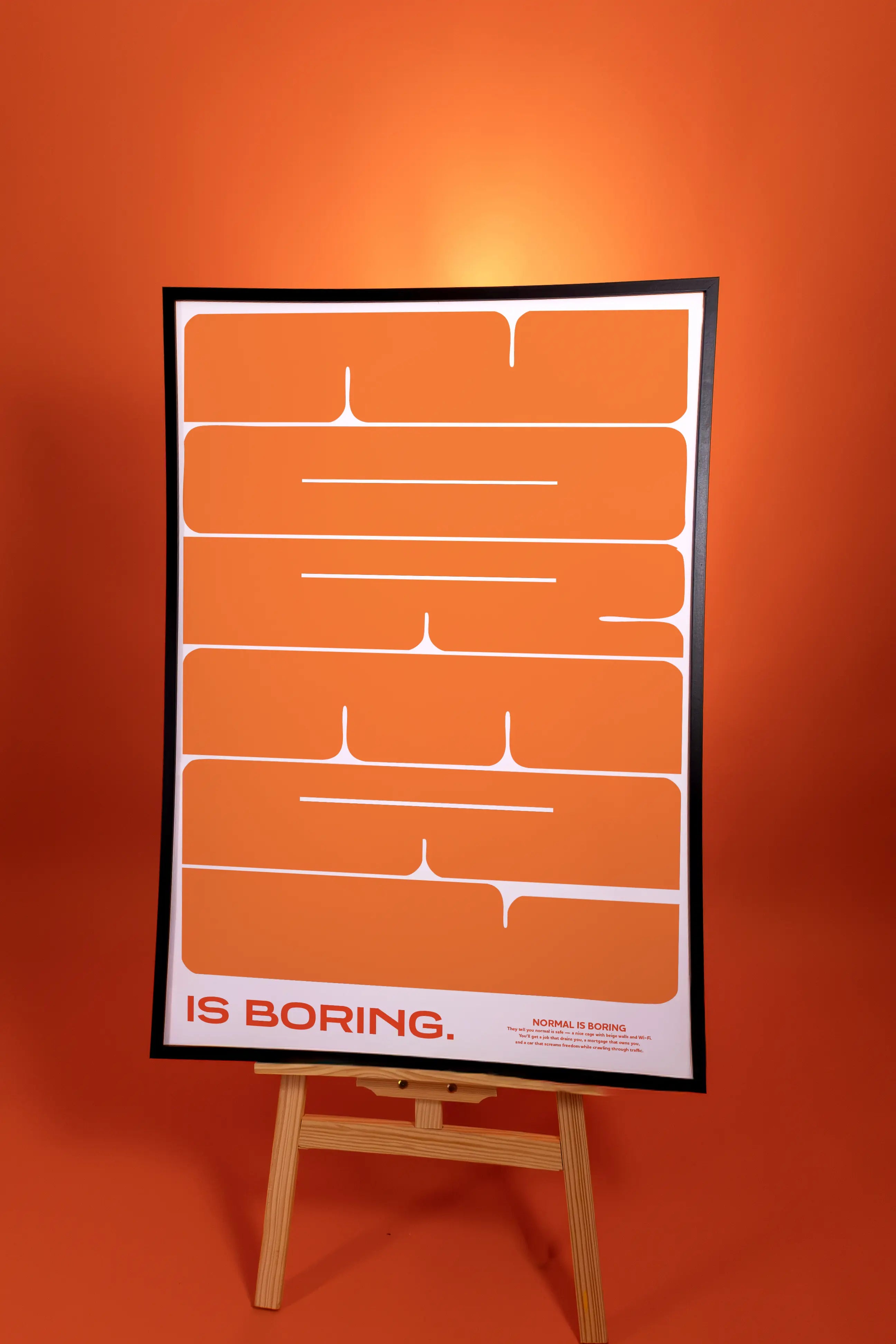Poster with text 'IS BORING.' on an easel against an orange background