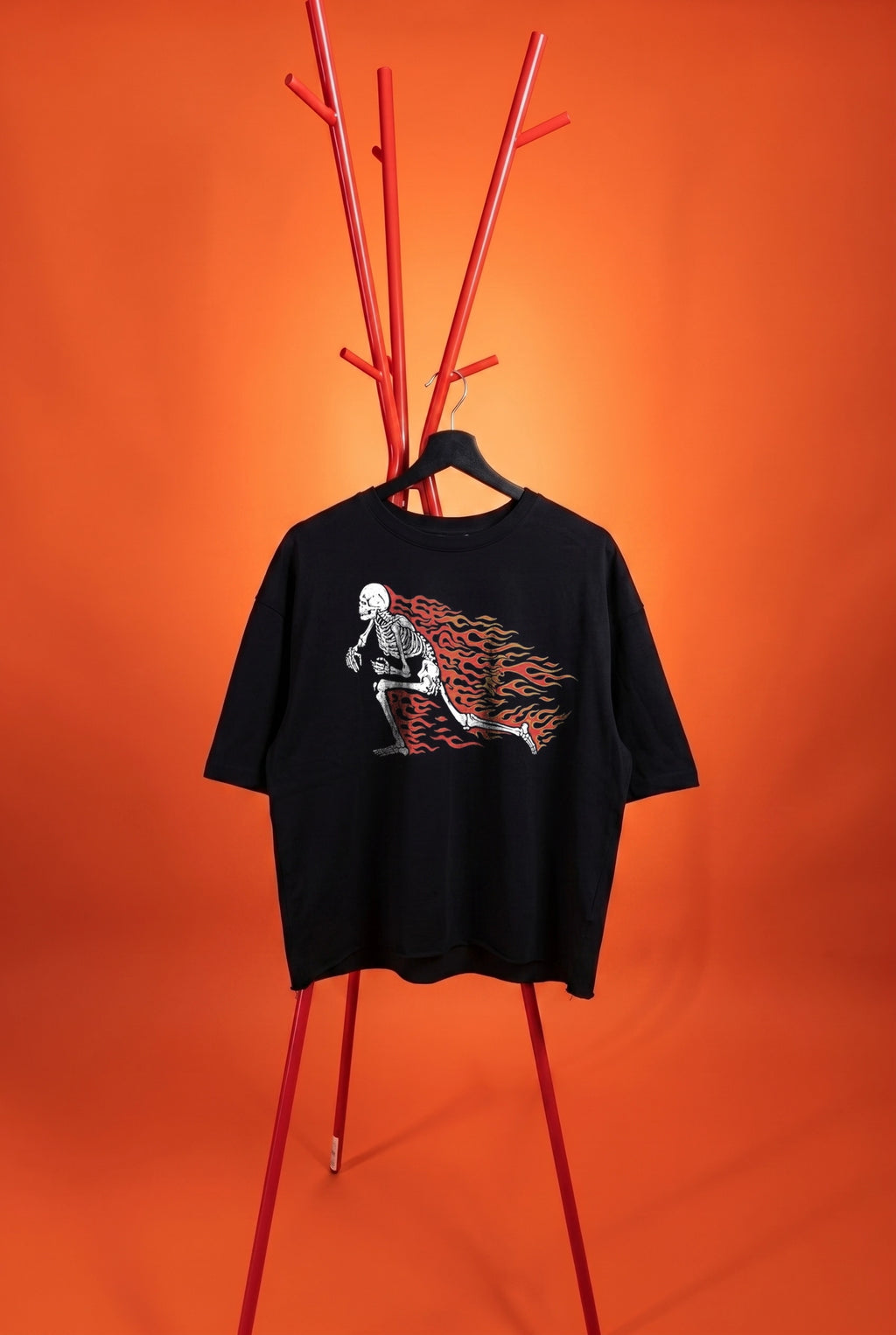Black t-shirt with graphic design on a hanger against an orange background