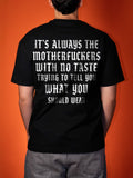 A person shown from the back wearing a black graphic t-shirt with a large white gothic-style text print on the back, set against a solid orange background.